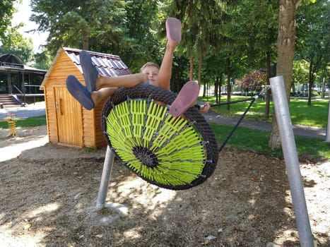 Sremska Mitrovica, Serbia, 13 September 2020. Children swing on a spider-web swing. Boy and girl, brother and sister in the summer on the playground. Swinging the swing.