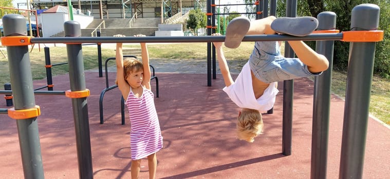 Sremska Mitrovica, Serbia, September 13, 2020. A boy and a girl on the sports or playground are engaged in physical exercise. Child in a white t-shirt. Girl in a striped dress laughs