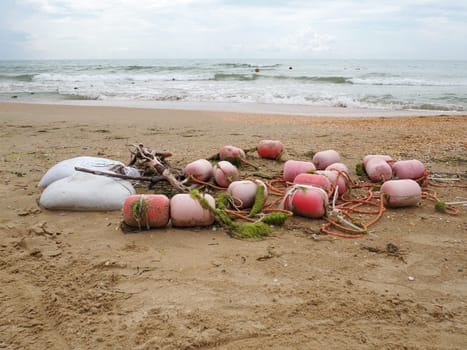 Buoys in the sand. A beach with wet coarse quartz sand. Tangled ropes and plastic buoys left on the shore. Safety equipment. The end of the summer season. Stormy weather at sea or ocean. Low tide