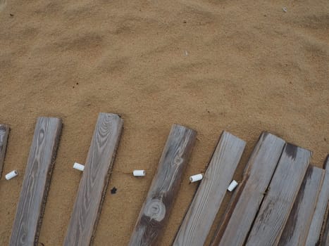 Wooden footbridge on a sandy beach. Uneven, damp wooden planks held together. The edge of the beach season at the hotel. No people, copy space. Equipped sandy beach after a storm or cyclone. Tourism.