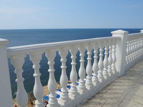 Anapa, Russia 23 August 2021. Balustrade overlooking the sea, sky and horizon, a fence consisting of a row of curly posts of balusters connected by a horizontal beam. Railing from curly white posts