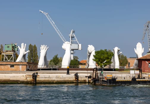 Venice, Italy - September 6, 2022: Giant joined hands sculpture Building Bridges by Lorenzo Quinn. Exhibition at Arsenale, Castello, Venice