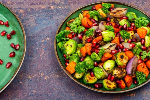 Salad with grilled brussels sprouts, roasted carrots, garnished with herbs and pomegranate seeds. Top view