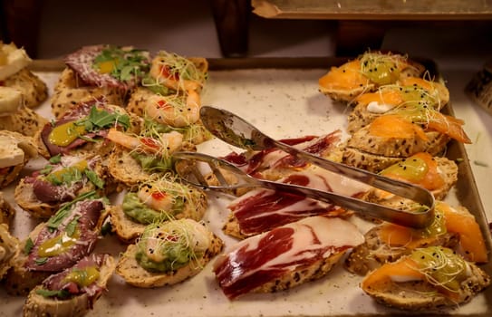 Many bites with cheese and ham in a tapas bar.