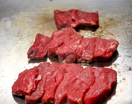 Still raw beef lies on a hot surface for frying.
