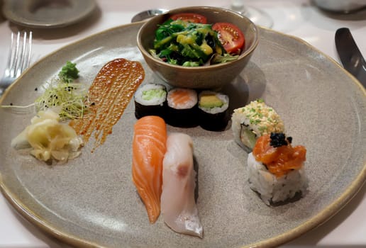 A plate of salad and sushi rolls, fresh raw fish.