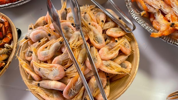 On a buffet is a bowl of cooked shrimp.