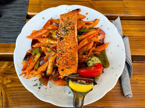 A plate of penne, pasta, vegetables and salmon.