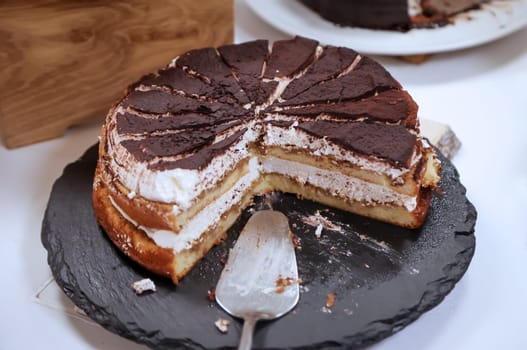 A cut chocolate cream cake with pieces already missing.