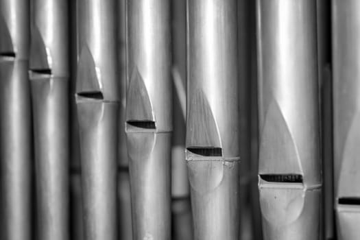 Many organ pipes stand side by side in an organ over a bellows.