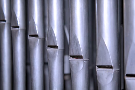 Many organ pipes stand side by side in an organ over a bellows.