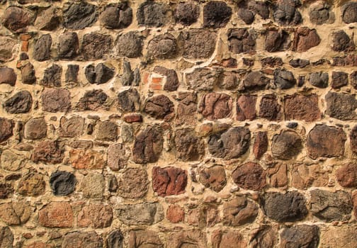A stone wall made of many quarry stones. A texture of a stone wall.