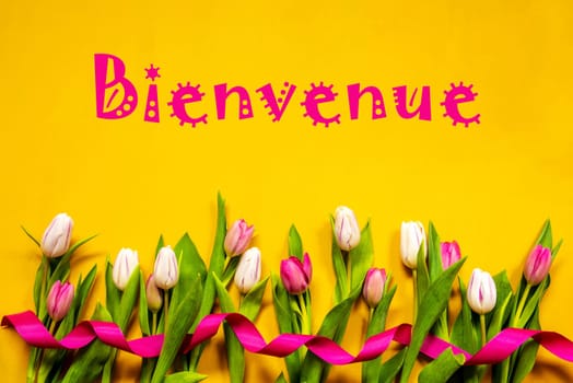 French Text Bienvenue Means Welcome. White And Pink Tulip Spring Flowers With Ribbon. Yellow Wooden Background
