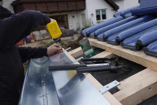 Dachdecker befestigt ein Traufblech auf Dachlatten