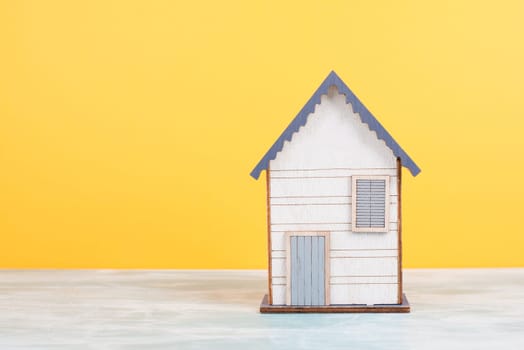 Wooden house, yellow background, buying or renting a house, real estate concept, booking home for vacation, owning property