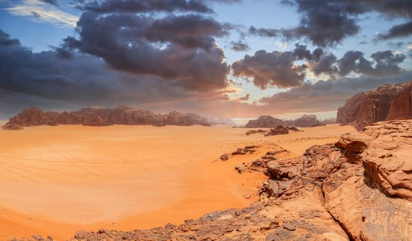 Red sands, mountains, dramatic sky and marthian landscape panorama of Wadi Rum desert, Jordan