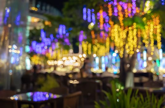 Blur abstract background of outdoors cafe or restaurant with colorful night bokeh illuminated lights decoration