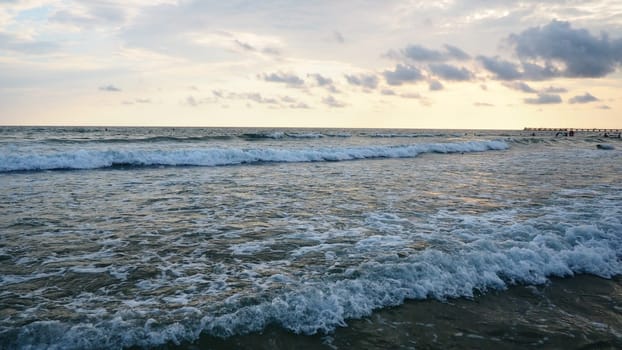 Sunset over the sea. Beautiful waves at sunset. Tourist mecca, resort. Evening sky. The rays are reflected from the water