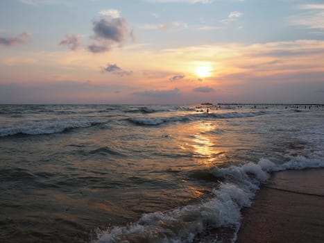 Sunset over the sea. Beautiful waves at sunset. Tourist mecca, resort. Evening sky. The rays are reflected from the water