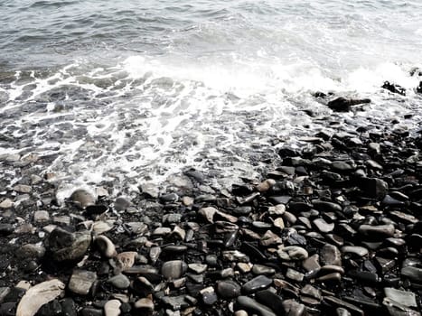 Sea rocky beach with waves Sukko, Anapa, Krasnodar Territory, Russia. Sea foam on a pebble beach view from above. Large rounded pebbles and boulders in the water. Horizontal photo Black Sea, Caucasus