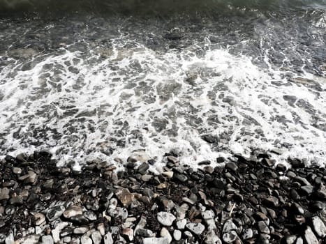 Sea rocky beach with waves Sukko, Anapa, Krasnodar Territory, Russia. Sea foam on a pebble beach view from above. Large rounded pebbles and boulders in the water. Horizontal photo Black Sea, Caucasus