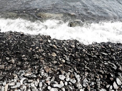 Sea rocky beach with waves Sukko, Anapa, Krasnodar Territory, Russia. Sea foam on a pebble beach view from above. Large rounded pebbles and boulders in the water. Horizontal photo Black Sea, Caucasus