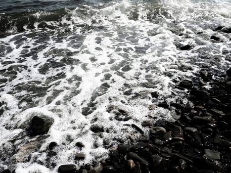 Sea rocky beach with waves Sukko, Anapa, Krasnodar Territory, Russia. Sea foam on a pebble beach view from above. Large rounded pebbles and boulders in the water. Horizontal photo Black Sea, Caucasus