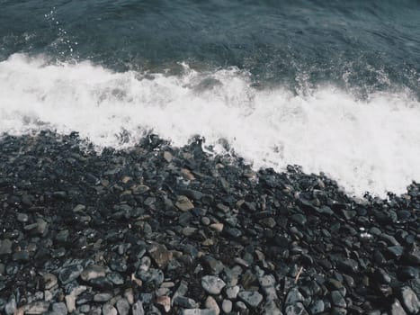 Sea rocky beach with waves Sukko, Anapa, Krasnodar Territory, Russia. Sea foam on a pebble beach view from above. Large rounded pebbles and boulders in the water. Horizontal photo Black Sea, Caucasus
