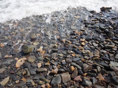 Sea rocky beach with waves Sukko, Anapa, Krasnodar Territory, Russia. Sea foam on a pebble beach view from above. Large rounded pebbles and boulders in the water. Horizontal photo Black Sea, Caucasus