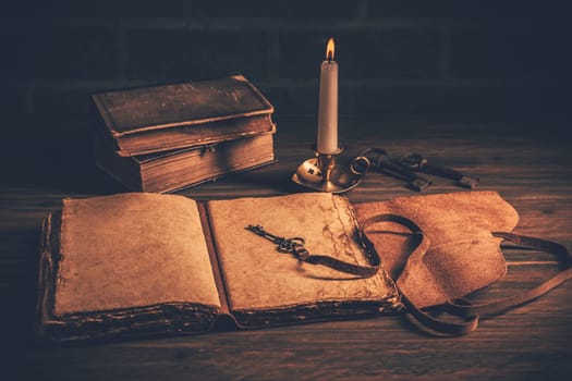 Old antique books with candle on wooden background