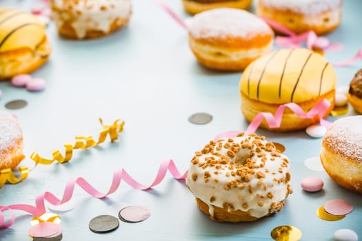 German Krapfen or donuts with streamers and confetti. Traditional Berliner for carnival and party.. Colorful carnival or birthday image