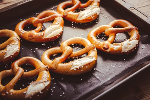 Fresh baked homemade German pretzel with sea salt on baking sheet. Classic beer snack, baked pastry.