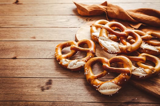 Fresh baked homemade German pretzel with sea salt on wooden table. Classic beer snack, baked pastry.