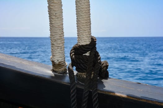 Part of an old sailing ship with ropes and facing the open sea