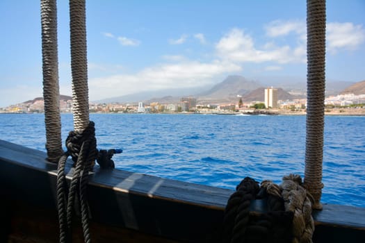 Ropes from an old sailing ship overlooking the blurred Los Cristianos coastline on the Canary Island of Tenerife, Spain