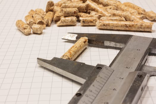 Quality control of certified wood pellets with caliper and sieve on chequered paper