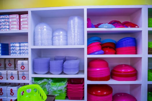 Colorful plastic tableware on shelves in the super shop. Close-up.