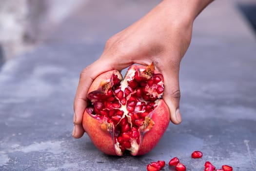 woman hand holding pomegranate fruit on grunge background.
