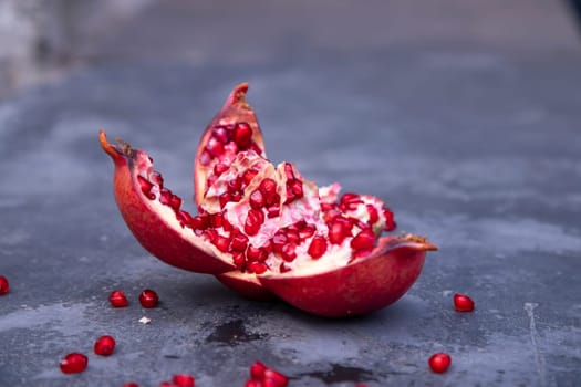 Ripe pomegranate fruit on a dark stone background.
