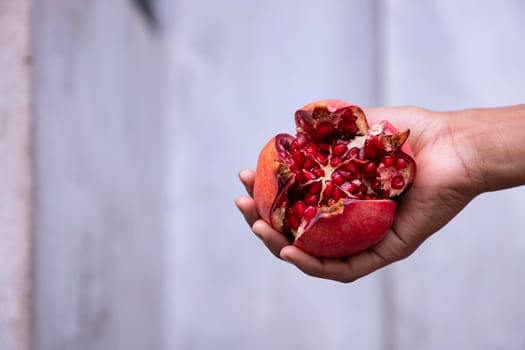 Ripe pomegranate fruit in hand on white background.
