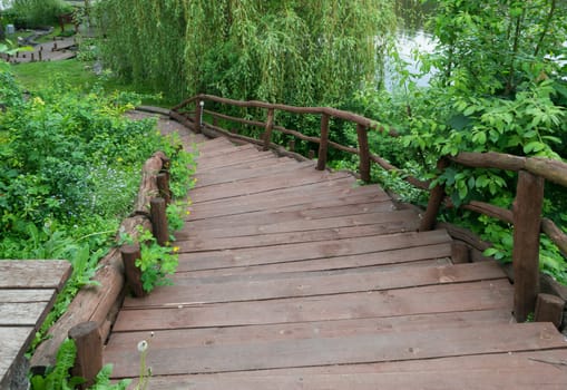 Old wooden curved staircase leading down to the lake shore of the pond