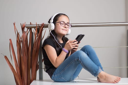 Cute happy girl with glasses listening to music on headphones