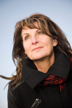 Head-port of a middle-aged woman in front of blue sky joyfully to the side and looking up