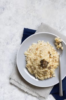 Risotto with wild porcini mushrooms and black truffles from Italy served in a plate top view on white table, copy space. Eating Italian gourmet cousine