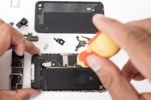 Technician repairing inside the smartphone motherboard with tools for recovery, The man repair by tightening nut from mobile phone with a screwdriver to fix problem