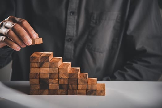 Business hand arranging put wooden block stacking step stair growth success process, financial risk management and strategic plan and business challenge planning concept, prevent collapse or crash