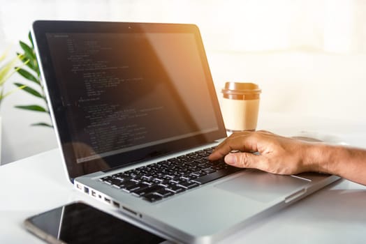 Web application development. programmer woman writing program code sitting at workplace in office, software developer hands coding HTML programming with laptop computer, IT start up concept, back view
