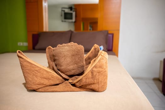 Yellow towel on bed decoration in bedroom interior, Freshly laundered fluffy towels, Towel in hotel room, Beautifully folded toiletries