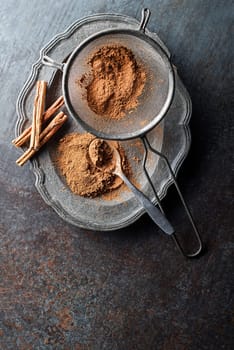 Aromatic cinnamon sticks and powder on grey rustic background close up