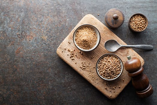 Organic Dried coriander seeds (Coriandrum sativum) and powder on rustic background. Healthy eating, Indian spice, flavoring, vitamin.